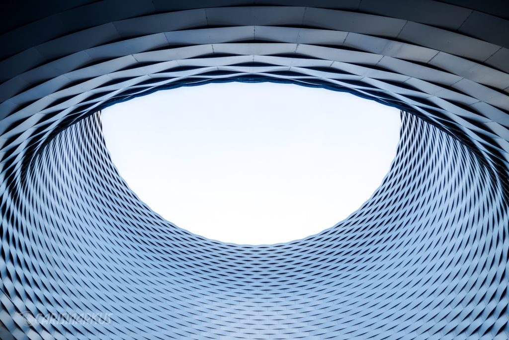 Architekturdetail mit organischer Fassadenstruktur und ovaler Öffnung, moderne Architektur abstrakt fotografiert